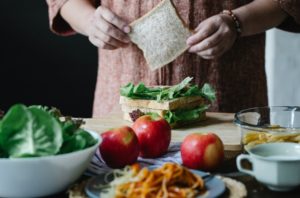 crop woman making sandwich with salad