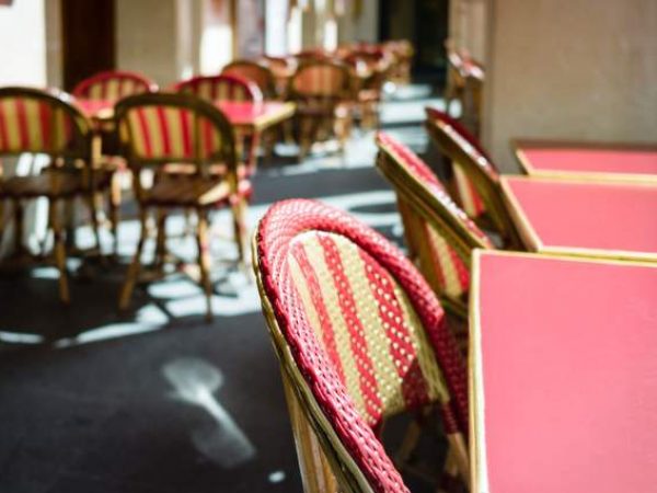 Canva - Typical tables and rattan chairs on the terrace of a parisian outdoor cafe in the sunlight (1).jpg