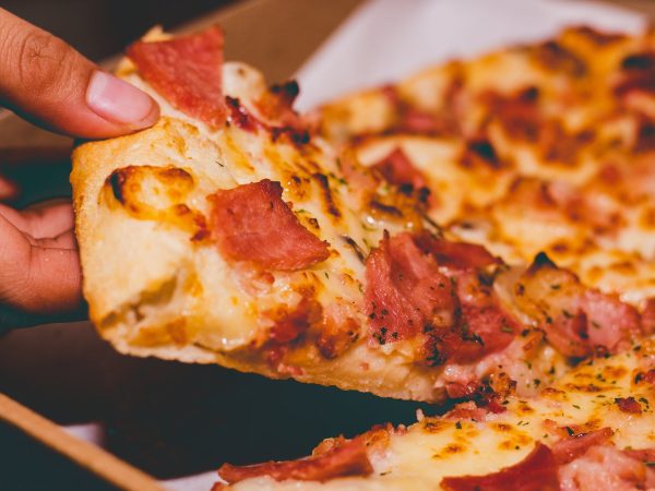 close up photo of person holding pizza