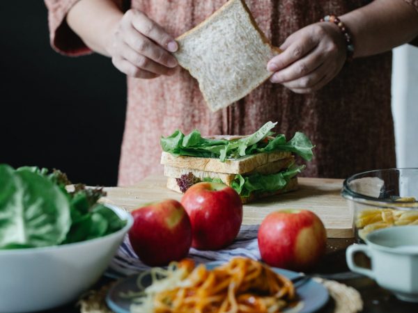 crop woman making sandwich with salad