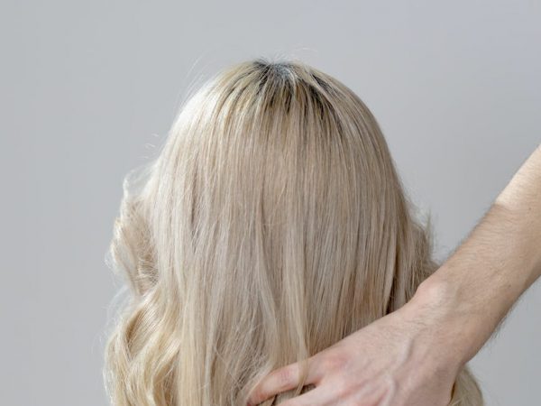 blonde woman covering her face with her hands